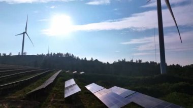 Kırsal kesimdeki güneş panelleri ve rüzgar türbinlerinin hava görüntüsü, yenilenebilir enerji kaynağı