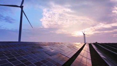 Kırsal bölgedeki güneş panelleri ve rüzgar türbinlerinin günbatımı görüntüsü, yenilenebilir enerji kaynağı