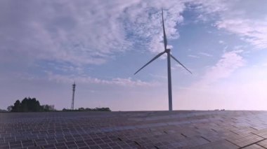 Kırsal kesimdeki güneş enerjisi panelleri ve rüzgar türbinlerinin günbatımı görüntüsü, yenilenebilir enerji kaynağı