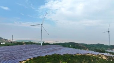 Kırsal kesimdeki güneş panelleri ve rüzgar türbinlerinin hava görüntüsü, yenilenebilir enerji kaynağı