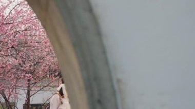 Bahar bahçesindeki güzel kiraz ağacının yanında Asyalı bir kız