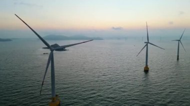 Gün batımında denizdeki rüzgar türbinlerinin hava görüntüsü