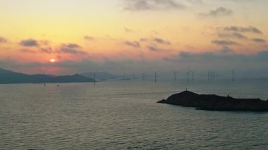 Gün batımında denizdeki rüzgar türbinlerinin hava görüntüsü