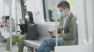 İnsanlar modern metro vagonunda akıllı telefon kullanıyorlar.
