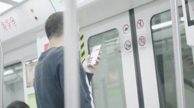 Modern metro vagonunda akıllı telefon kullanan adam.