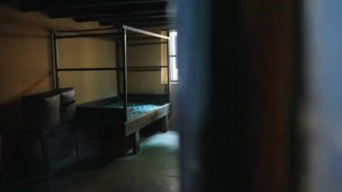 İçinde yatak ve pencere olan eski bir hapishane odası.