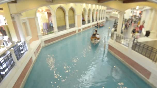 マカオのヴェネツィアのラグジュアリーホテルとカジノとモールの運河を通ってロマンチックな乗り物で観光客を取るゴンドリア — ストック動画