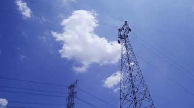 Elektrik direği ve elektrik hatları mavi gökyüzü arkaplanına karşı