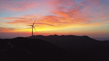 Rüzgar türbini gün batımında dağlardaki rüzgar enerji istasyonunda dönüyor..