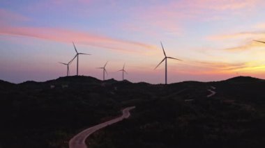 Rüzgar türbinleri güneşin doğuşunda dağlardaki rüzgar enerji istasyonunda dönüyor..