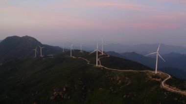 Rüzgar türbinleri güneşin doğuşunda dağlardaki rüzgar enerji istasyonunda dönüyor..