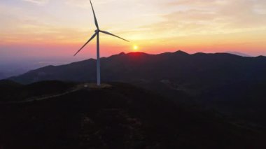 Rüzgar türbini gün batımında dağlardaki rüzgar enerji istasyonunda dönüyor..