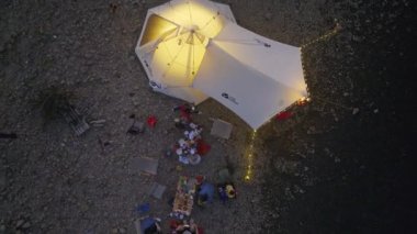 Kampçılar, nehir kıyısındaki ateşin etrafında toplanan bir akşamın keyfini çıkarırlar. 