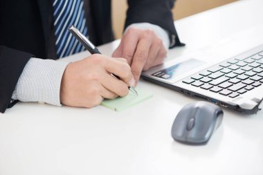 İşadamlarının elleri masanın üzerinde dizüstü bilgisayar ve kalemle çalışıyor.