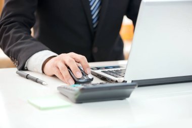 İşadamlarının elleri masanın üzerinde dizüstü bilgisayar ve kalemle çalışıyor.