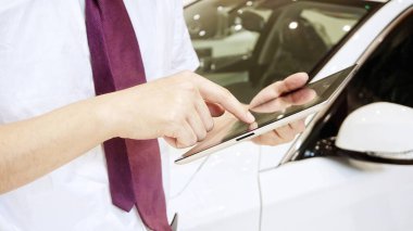 Genç işadamı araba dükkanında tablet bilgisayar kullanıyor.