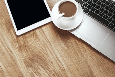 Tahta masadaki dizüstü bilgisayarda bir fincan kahve.