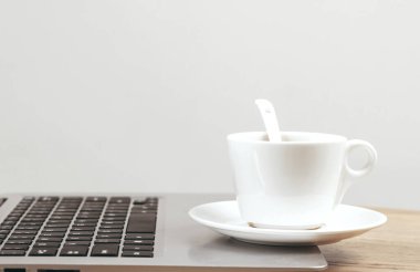 Laptop ve bir fincan kahve tahta masada. 