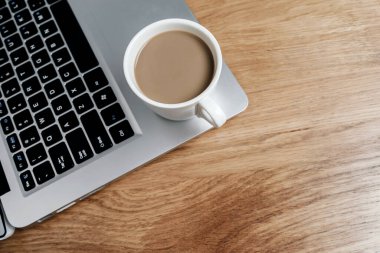 Laptop ve bir fincan kahve tahta masada. 