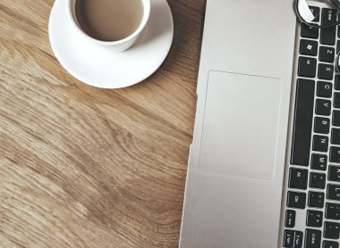 Laptop ve bir fincan kahve tahta masada. 