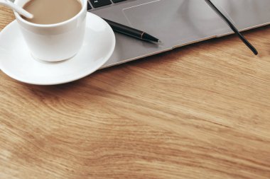 Bilgisayarlı, kahveli ve defterli ofis masasının üst görüntüsü.