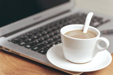 Laptop ve bir fincan kahve tahta masada. 