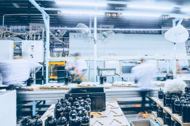 Üretim atölyesindeki sahne, işçilerin bulanık görüntüsü          