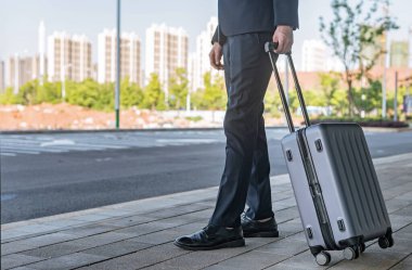 Şehir caddesinde bavul taşıyan bir adam.