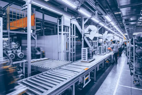 Üretim atölyesindeki sahne, işçilerin bulanık görüntüsü          