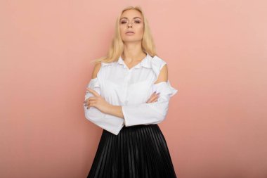 Beauty, fashion portrait. Elegant business style. Portrait of a beautiful blonde woman in white blouse and black skirt posing at studio on a pink background. clipart