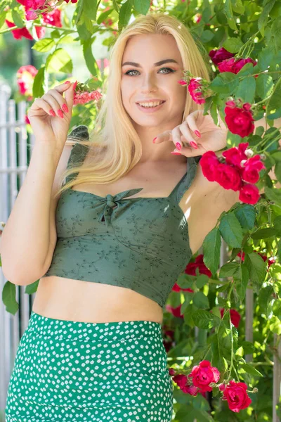 漂亮的金发女人在花园里摆姿势 穿着绿裙子和玫瑰T恤的高加索快乐女孩的画像 — 图库照片