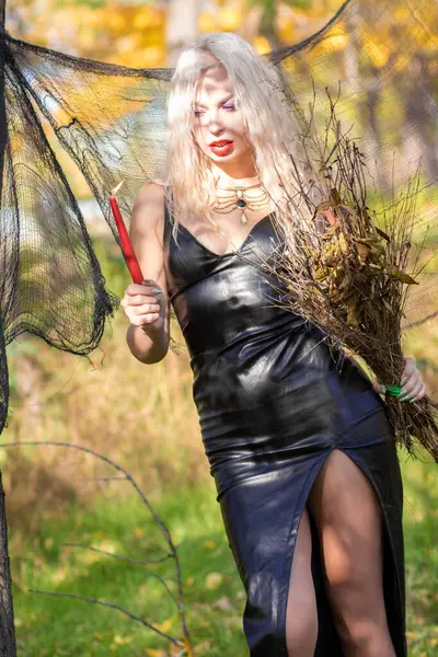 魔女のイメージに重い髪のブロンドの写真撮影 長い革のドレスと彼女の手のブロム ハロウィーンコンセプト — ストック写真