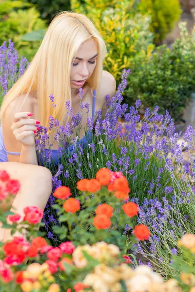 Leylak rengi bir elbisenin içinde uzun saçlı ve doğal makyajlı bir sarışının portresi lavanta çiçeklerinin arasında bir tarlada duruyor. Yaz sabahı