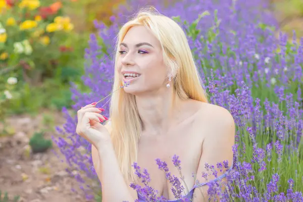 Leylak rengi bir elbisenin içinde uzun saçlı ve doğal makyajlı bir sarışının portresi lavanta çiçeklerinin arasında bir tarlada duruyor. Yaz sabahı