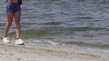 Denim Shorts ve White Sneakers 'la Nehir Kıyısında Yürüyen Genç Kadın