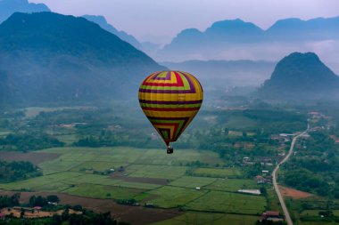 Sıcak hava balonu Vang Vieng, Laos 'taki Misty Dağı' nın üzerinde yüzüyor.