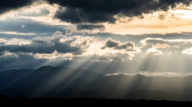 Yüksek dağdaki bulutların arasından ışık huzmesi, güzel bir manzara.