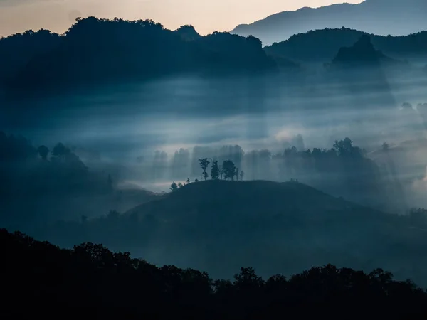 晨阳的光芒穿过山中的雾气 免版税图库图片