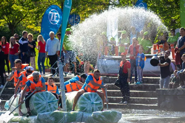 Timisoara, Romanya - 11 Eylül 2021: İnsanlar yarışmacılara su fırlatıyor. Birincilik ödülü için yarışan geri dönüşümlü malzemeden yapılmış tekneler
