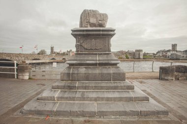İrlanda kavramını keşfet. Shannon Nehri üzerindeki Thomond Köprüsü 'nün ve Limerick şehrindeki Kral John' un Kalesi 'nin arkasındaki Antlaşma Taşı' na bakın. Hava bulutlu. Kartpostal stili. Açık hava çekimi