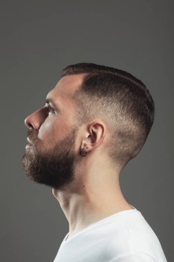 Male beauty concept. Profile portrait of charismatic active 30-year-old man posing over gray background. Perfect haircut. Poster style. Close up. Studio shot