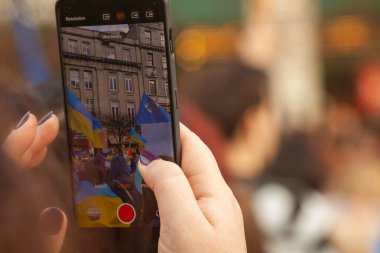 Ukraynalılar ve destekçiler toplanıyor. Rusya 'nın Ukrayna' yı işgalinin birinci yıldönümü. Cep telefonunda el çekimi toplantısı. Kapatın. Metin uzayı. Açık hava çekimi