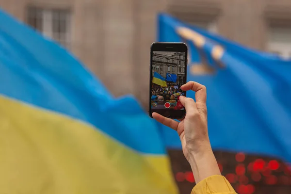 stock image Ukrainians and supporters rally. The first anniversary of Russia's invasion of Ukraine. Hand shooting meeting on mobile phone. Close up. Copy space. Outdoor shot