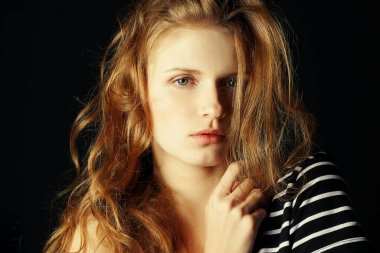 Modern Venüs konsepti. Siyah arka planda siyah ve beyaz çizgileri olan modaya uygun bir t-shirt 'ün portresi. Çembersel parlak kızıl saçlar, temiz cilt. Doğal makyaj malzemesi. Kapatın. Stüdyo çekimi