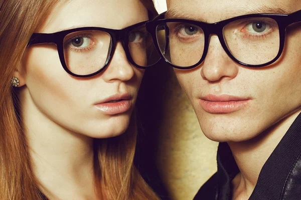Eyewear concept. Gorgeous red-haired fashion twins in wearing trendy glasses and posing together. Natural make-up. Perfect skin. Close up. Studio shot.