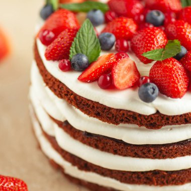 Pastane, şekerci dükkanı konsepti. Farklı taze böğürtlenlerle süslenmiş harika çikolata ve kremalı pastanın yakın plan görüntüsü. Doğal ışık. Kapalı çekim