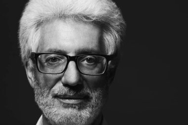 Herhangi bir yaş kavramı, yakışıklı. 60 yaşındaki adam koyu gri arka plan üzerinde ayakta portresi. Yakın çekim. Boşluk. Stüdyo vurdu