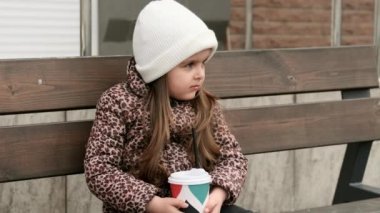 Küçük kız, kağıt bardaktan sıcak kakao içiyor..