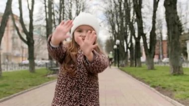 Anaokulu kızı sokakta dans ediyor, kamera önünde dans ediyor. Orta çekim.