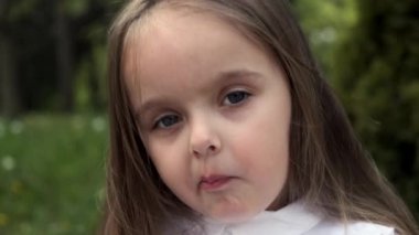 Neşeli küçük kız tatlı bir şeker çiğniyor, yüzüne yakın plan..